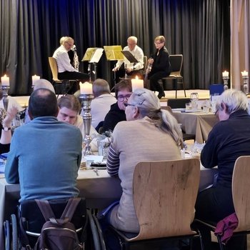 Ein Klarinettenquartett auf der Bühne und zuhörende Gäste im Saal