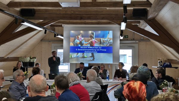 Michael Ledergerber als Geschäftsleiter steht neben der Leinwand und begrüsst zur 5. Generalversammlung