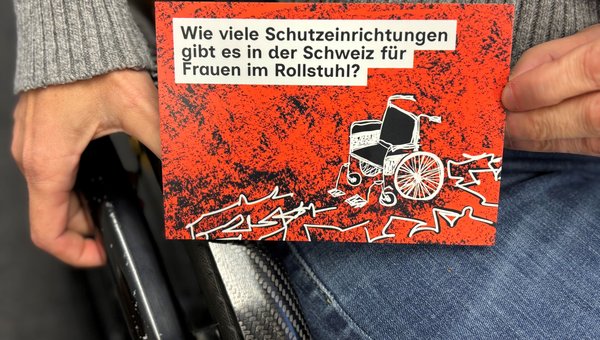 Rollstuhlfahrerin zeigt eine Postkarte