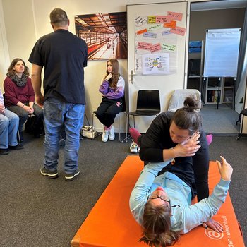 Rollstuhlfahrerin liegt am Boden und testet wie sie sich wehren kann