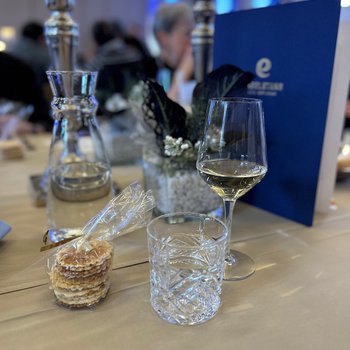 Bretzeli, ein Glas Wasser und ein Glas Weisswein vor der Weinkarte