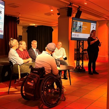 4 Podiumsteilnehmende und 1 Moderator und Gebärdendolmetscherin